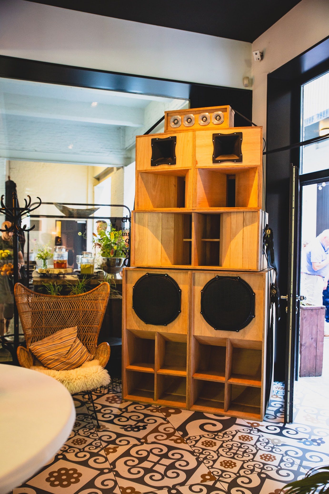Het sound system van Dubwave op een receptie: een stapel handgebouwde houten luidsprekerkasten naast een rieten zetel en een buffet